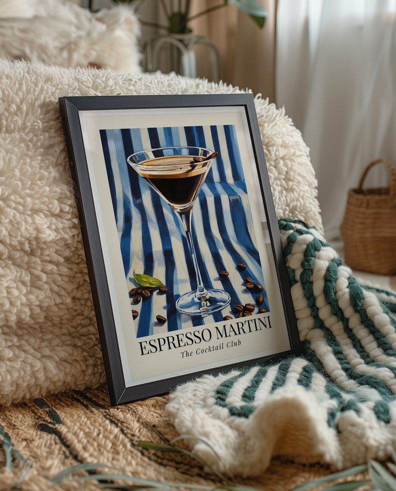 May include: A framed print of an espresso martini cocktail in a martini glass on a blue and white striped background with coffee beans scattered around the glass. The text "Espresso Martini" and "The Cocktail Club" is printed below the glass.