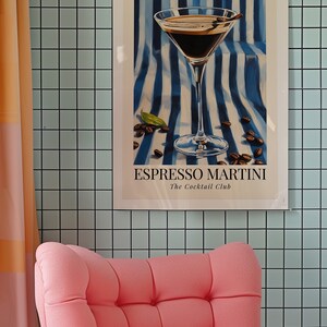 May include: A framed poster with a blue and white striped background featuring a martini glass filled with a dark liquid. The text on the poster reads "Espresso Martini The Cocktail Club".