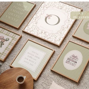 May include: A collection of framed art prints with a soft, vintage aesthetic. The prints feature various designs, including an alphabet, floral patterns, a teddy bear with balloons, a butterfly, and a stack of books. The color palette includes muted greens, pinks, and creams.