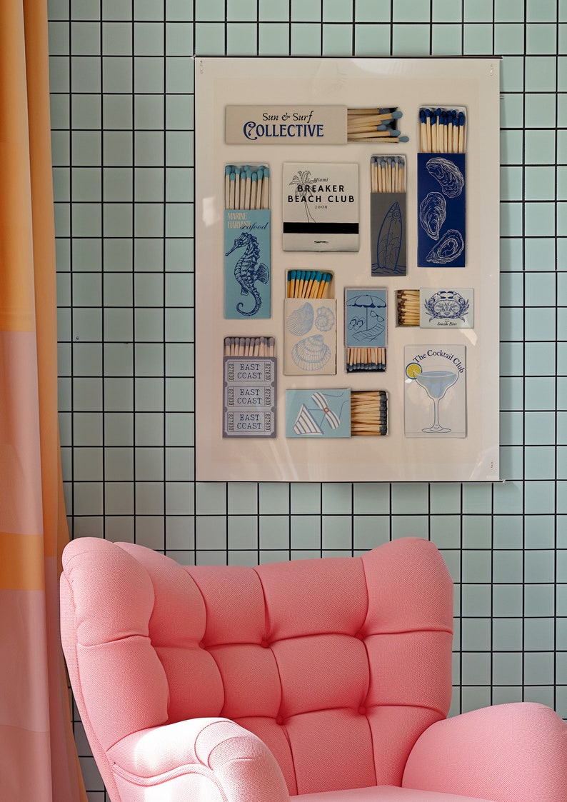 May include: A white framed poster with a collection of matchboxes featuring various designs, including seashells, a cocktail glass, and a surfboard. The poster is titled "Sun & Surf Collective" and is displayed on a light blue tiled wall.