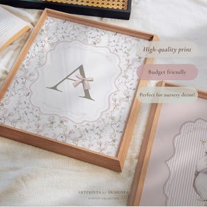 May include: Wooden framed print featuring the letter "A" with a pink bow, set against a floral background. The print is in a wooden frame. The text "High-quality print" and "Budget friendly" are visible.