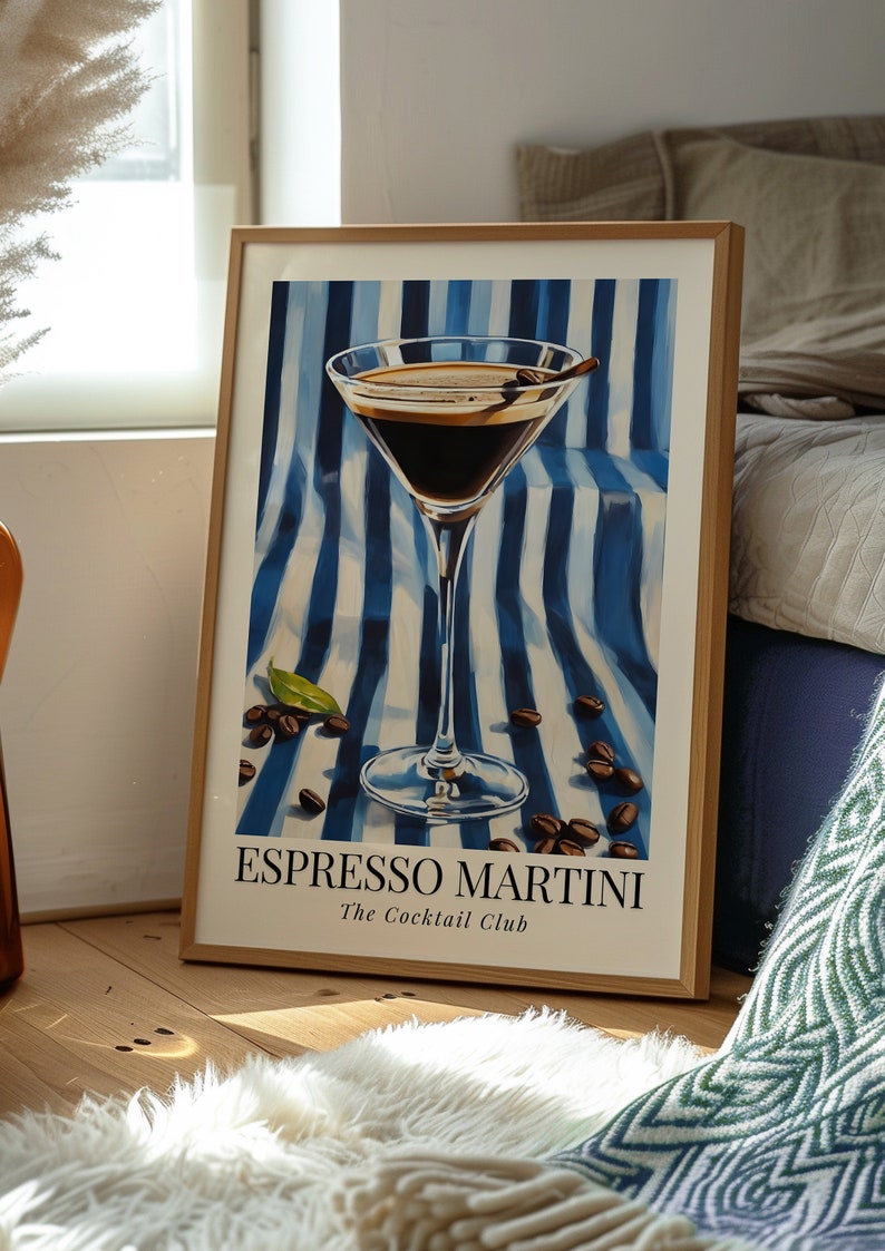 May include: A framed poster with a blue and white striped background featuring a martini glass filled with a dark brown liquid. The glass has a cinnamon stick garnish. The text "Espresso Martini The Cocktail Club" is printed below the glass.