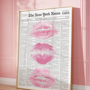 May include: A framed print with a newspaper design and three pink lip imprints. The headline reads "The New York News" with the date "Sunday, July 27, 2025". The frame is gold-coloured.