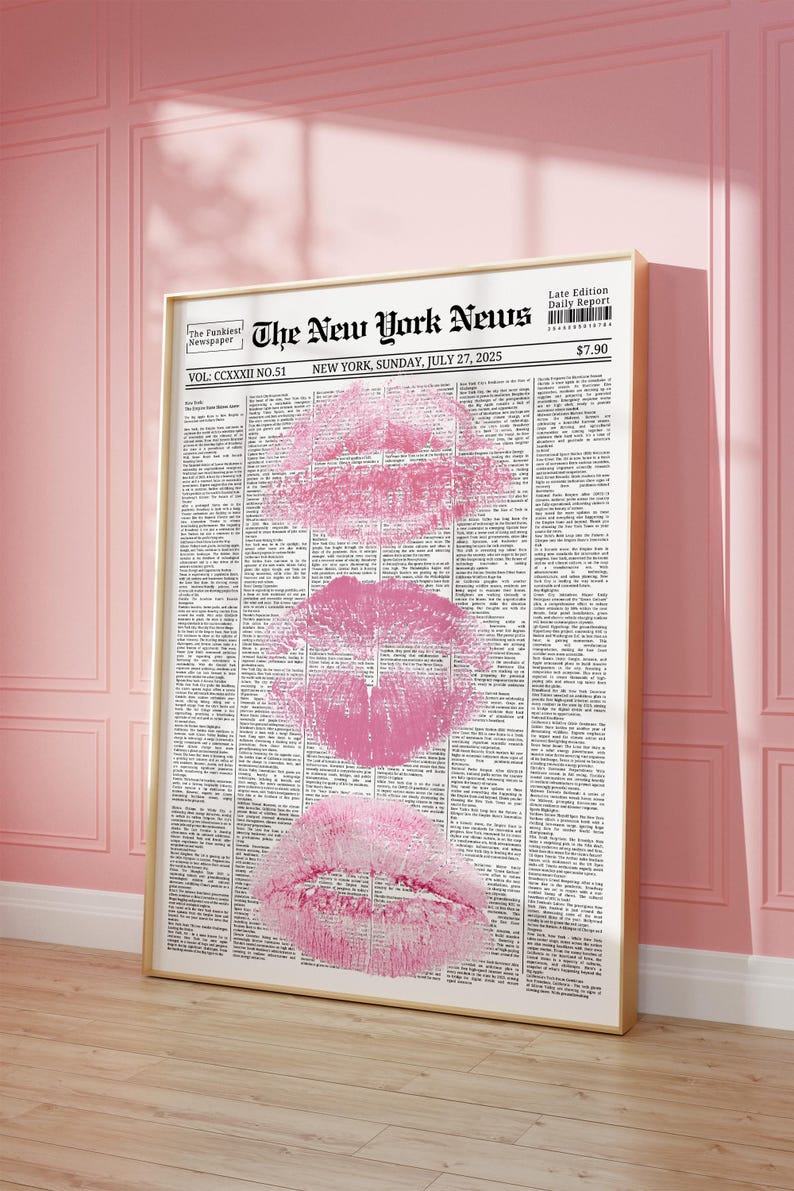 May include: A framed print with a newspaper design and three pink lip imprints. The headline reads "The New York News" with the date "Sunday, July 27, 2025". The frame is gold-coloured.