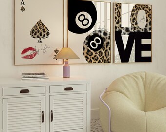 May include: Three framed prints with a leopard print background. The left print features a playing card with a leopard print spade and the text "Lucky You". The middle print features two black and white billiard balls with the number eight on them. The right print features the word "LOVE" in black with the text "Lucky in Love" in the top right corner.