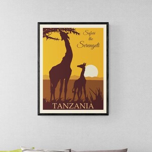 May include: A framed poster with a yellow background featuring a silhouette of two giraffes in front of a setting sun. The text "Safari in the Serengeti" and "TANZANIA" are printed below the giraffes.