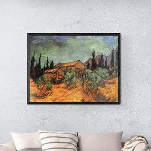 Può includere: Un divano grigio chiaro con una coperta e cuscini in un soggiorno con un dipinto incorniciato di un paesaggio con una casa e alberi. Il dipinto è in una cornice di legno scuro. Il divano è di fronte a una parete grigio chiaro. Il pavimento è in legno chiaro.