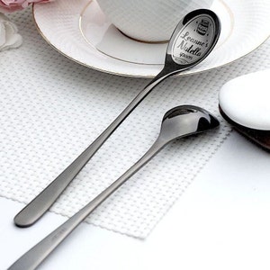 Könnte beinhalten: Zwei schwarze Löffel aus Metall. Ein Löffel hat den Text "Leanne's Nutella spoon" auf der Schale eingraviert.