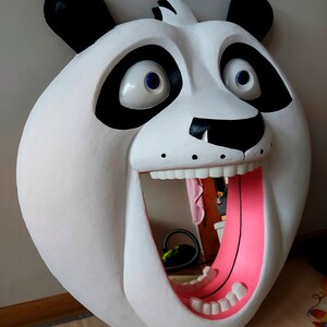 Puede incluir: Una gran escultura de cabeza de panda blanca con orejas y parches negros. La boca del panda est&aacute; abierta, revelando una lengua rosa y dientes blancos. Los ojos son grandes y azules. La escultura est&aacute; dise&ntilde;ada para montarse en la pared.