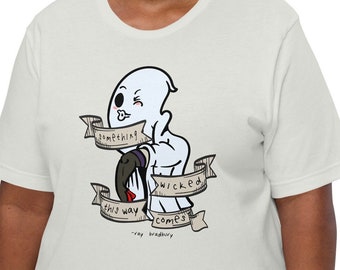 May include: Off-white t-shirt featuring a cartoon ghost winking and giving a thumbs up. The ghost holds a banner that reads "something wicked this way comes" with the author's name. The shirt is a casual, unisex style.