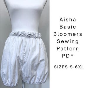 May include: White bloomers with an elasticated waistband and leg openings displayed on a mannequin. The text reads: Aisha Basic Bloomers Sewing Pattern PDF SIZES S-6XL. These shorts feature a gathered, voluminous silhouette and a solid white colour.