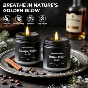 May include: Two black jar candles with lit flames, labeled "Mahogany Coffee" and "Balsam Cedar." The image includes cinnamon sticks, coffee beans, and text that reads "Breathe in Nature's Golden Glow." The candles are 3 oz.