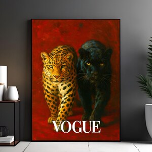 May include: Framed art print featuring a leopard and a black panther against a red background. The word "VOGUE" is printed in white at the bottom. The artwork is displayed next to a side table with a candle and a potted plant.
