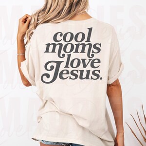 May include: Cream-colored t-shirt with the text "cool moms love Jesus" in a dark gray, bold font. The shirt has short sleeves and a relaxed fit, suitable for casual wear.