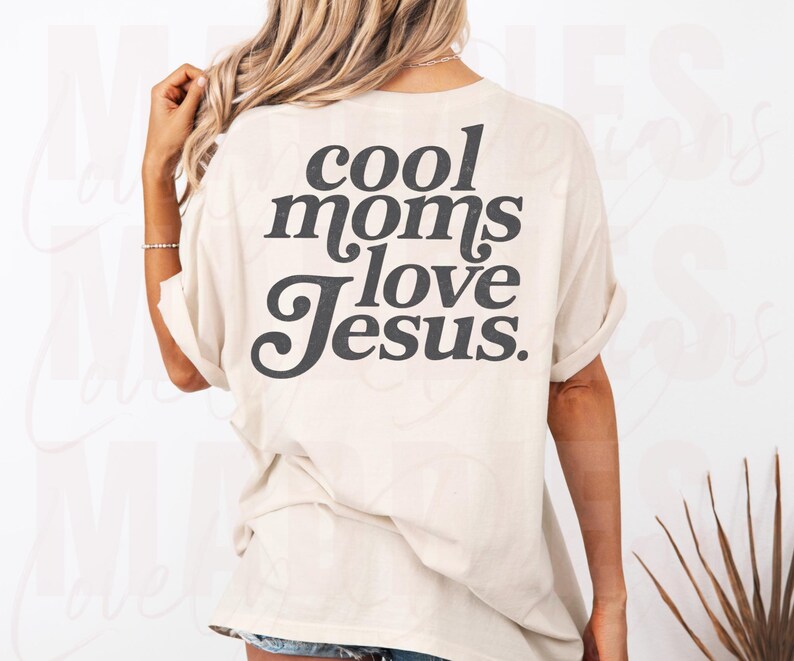 May include: Cream-colored t-shirt with the text "cool moms love Jesus" in a dark gray, bold font. The shirt has short sleeves and a relaxed fit, suitable for casual wear.
