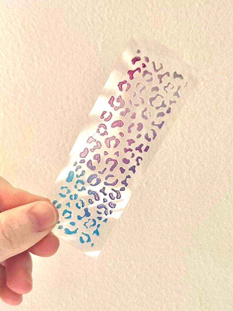May include: A sheet of clear vinyl with a repeating pattern of iridescent blue, purple, and pink leopard spots.
