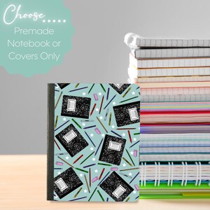 May include: A light blue notebook with a repeating pattern of black composition notebooks, colored pencils, and pink erasers against a background of white stars. To the right, a tall stack of various notebooks with different colored edges.