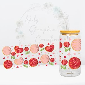 Op de afbeelding: Een glazen pot met een houten deksel en een rietje. De pot is versierd met een patroon van roze en rode harten, bloemen en swirls. De pot is gevuld met een roze en rode vloeistof.