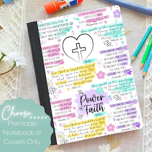 May include: A notebook with a black spine and a white cover featuring a central heart and cross icon. The cover is decorated with colorful handwritten Bible verses, floral doodles, and the text The Power of Faith in black script lettering.
