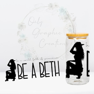 May include: A clear glass jar with a wooden lid and a straw. The jar has a black silhouette of a woman wearing a cowboy hat and boots. The text "In a world full of princesses, BE A BETH" is printed on the jar.