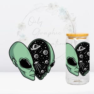 May include: A clear glass can-shaped tumbler with a bamboo lid and a reusable straw. The tumbler features a green alien head design with a starry galaxy interior. The design is repeated on the tumbler.