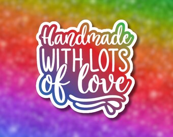 May include: A white sticker with the words "Handmade WITH LOTS of love" in a colorful gradient font. The sticker has a white border and is set against a rainbow background.