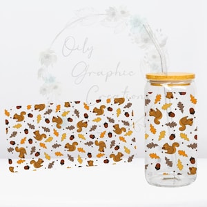 May include: A clear glass tumbler with a bamboo lid and a reusable straw. The tumbler features a repeating pattern of brown squirrels, acorns, and orange and brown leaves on a white background. The words "Oily Graphic Creations" are in the background.