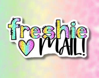 May include: A sticker with the text "freshie mail!" in black text with a rainbow heart with a leopard print pattern. The text "freshie" is in a rainbow color with a leopard print pattern.