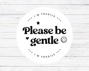 May include: White circle sticker with black text that reads "I'm Fragile. Please be gentle." with a star, heart, and smiley face.