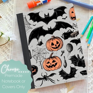 May include: A gray notebook cover with a Halloween-themed design. The cover features black bats, jack-o'-lanterns, spiders, and spiderwebs. The text "Choose Premade Notebook or Covers Only" is displayed on the bottom left.