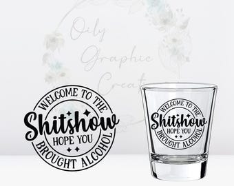 May include: A clear glass shot glass with a black and white graphic that reads "Welcome to the Shitshow Hope You Brought Alcohol".