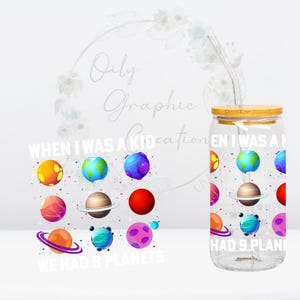 May include: A clear glass tumbler with a bamboo lid and a reusable straw. The tumbler features a colorful planet design with the text "WHEN I WAS A KID WE HAD 9 PLANETS".