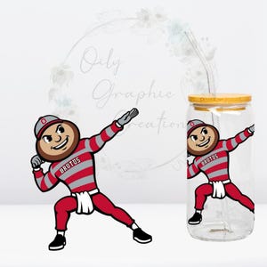 Puede incluir: Un vaso de cristal transparente con tapa de bambú y pajita de cristal, con un gráfico de la mascota Brutus haciendo el dab. La mascota lleva una camiseta de manga larga a rayas rojas y grises con la palabra BRUTUS y una gorra roja.