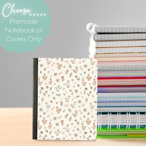 Puede incluir: Un cuaderno con una cubierta de color crema que presenta un patrón repetitivo de pequeños patos naranjas, corazones rosas y flores. Al lado hay una pila alta de varios cuadernos y diarios con páginas de colores y encuadernaciones en espiral.
