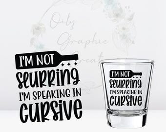 May include: A clear shot glass with the text "I'M NOT slurring I'M SPEAKING IN cursive" in black. The design is also on a separate black rectangle. The image has a light background with floral accents.