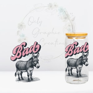May include: A clear glass jar with a bamboo lid and a pink and black donkey graphic with the word "Bad" in pink lettering. The jar has a straw in it.