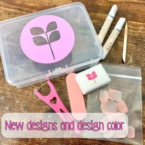 May include: A clear plastic box with a pink floral design, nail tools, and a bag of artificial nails. The image includes a pink nail file, a pink floss pick, and two tubes of nail glue. Text on the image reads "New designs and design color."