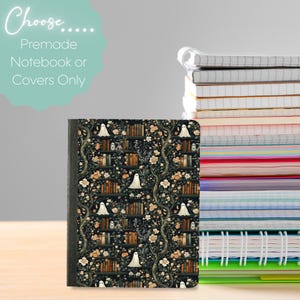 Könnte beinhalten: Ein Notizbuch mit einem Einband mit einem dunklen Blumen- und Bücherregal-Muster mit weißen Geisterillustrationen. Der Text "Choose... Premade Notebook or Covers Only" befindet sich in der oberen linken Ecke. Ein Stapel Notizbücher ist im Hintergrund zu sehen.