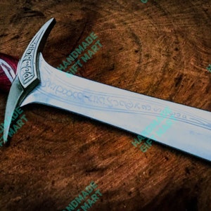 May include: A silver sword with a red and silver handle. The blade has intricate engravings and the words "For Frodo" are visible on the pommel.