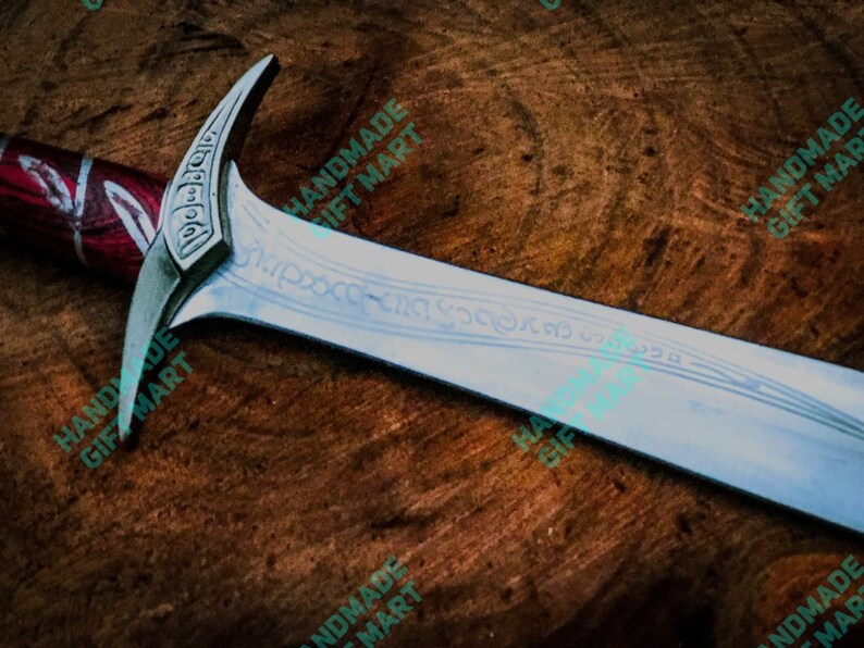 May include: A silver sword with a red and silver handle. The blade has intricate engravings and the words "For Frodo" are visible on the pommel.