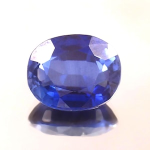 May include: A deep blue oval sapphire gemstone with a faceted cut.