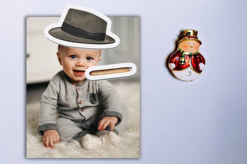 May include: A photo of a baby wearing a grey onesie and a fedora hat. A brown cigar is placed above the baby's mouth.