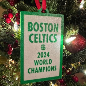 May include: Green and white Christmas ornament with the text "Boston Celtics 2024 World Champions" and the NBA logo.