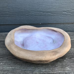 May include: An organic-shaped bowl with a light brown exterior and a swirling pink and white interior. The bowl is made of a natural material. Ideal for decorative use or as a unique serving piece. The bowl's dimensions are approximately 30 cm in diameter.