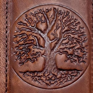 a close-up view of a brown leather surface with a circular embossed tree design.