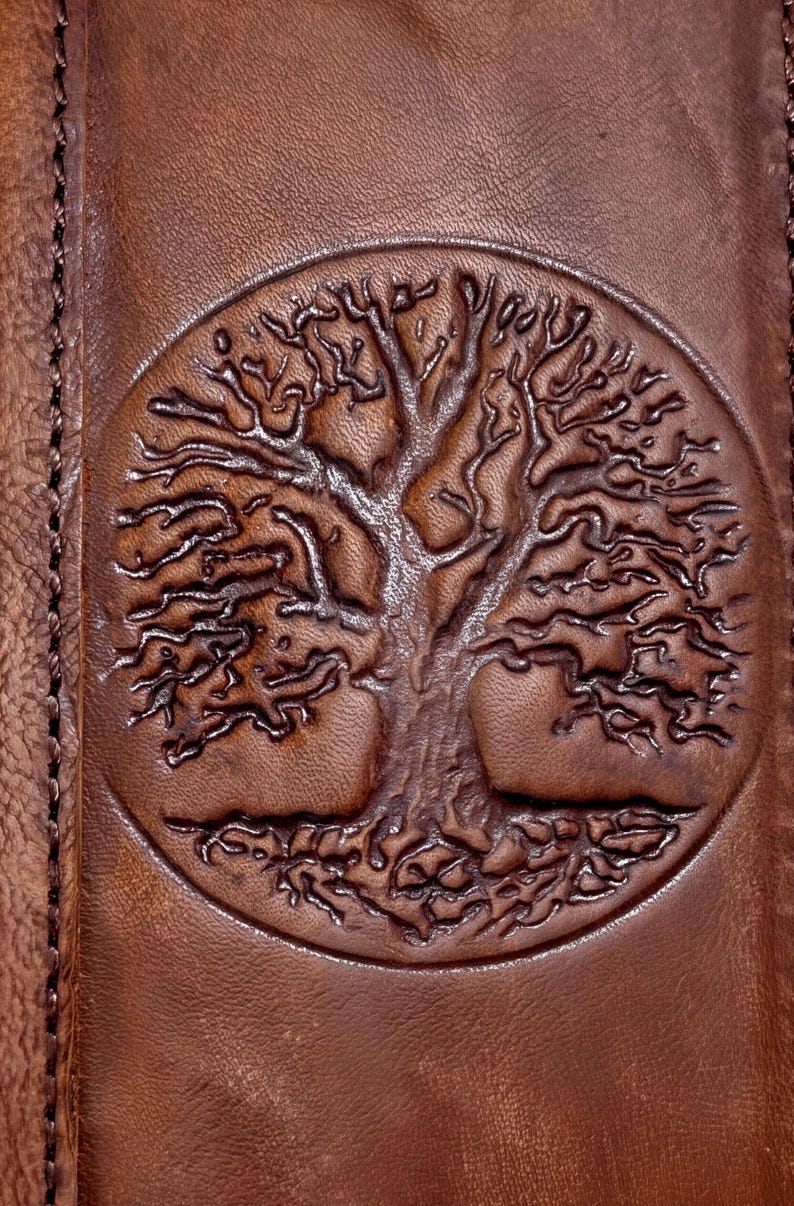 a close-up view of a brown leather surface with a circular embossed tree design.