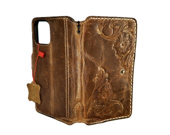 May include: A brown leather phone case with a floral design. The case has a flap that folds over the phone and snaps shut.