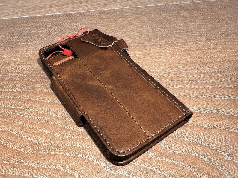 A brown leather wallet or fanny pack is placed on a wooden surface.