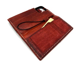 May include: Open, red leather wallet with white stitching. The wallet has a card slot and a black elastic strap. The interior is a lighter shade of red. The wallet is open, displaying the interior.