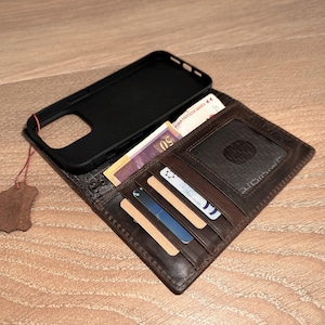 A brown leather wallet with a black case and various cards and cash inside is placed on a wooden surface.